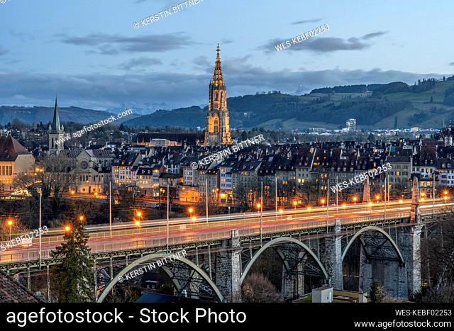 Switzerland, Canton of Bern, Bern, Kornhausbrucke bridge at dusk with bell tower of Cathedral of Bern in background
