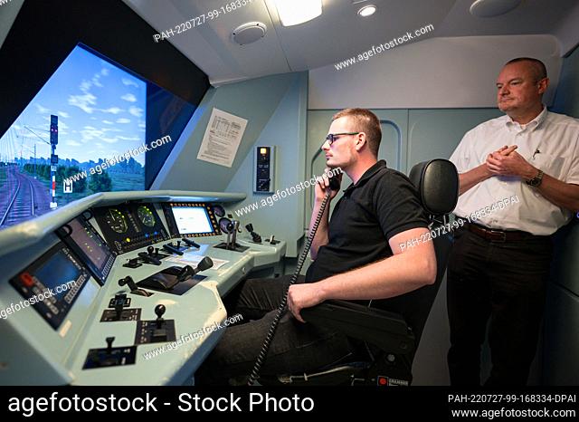 PRODUCTION - 30 June 2022, Saarland, Saarbrücken: Ulrich Pietsch, head of DB Training (r), looks on as Andreas Lutz sits at the driver's seat of the rail...