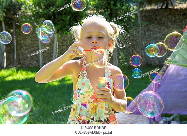 Girls blowing bubbles in summer garden party