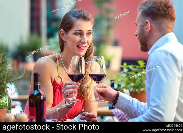Portrait of a happy couple toasting glass of red wine