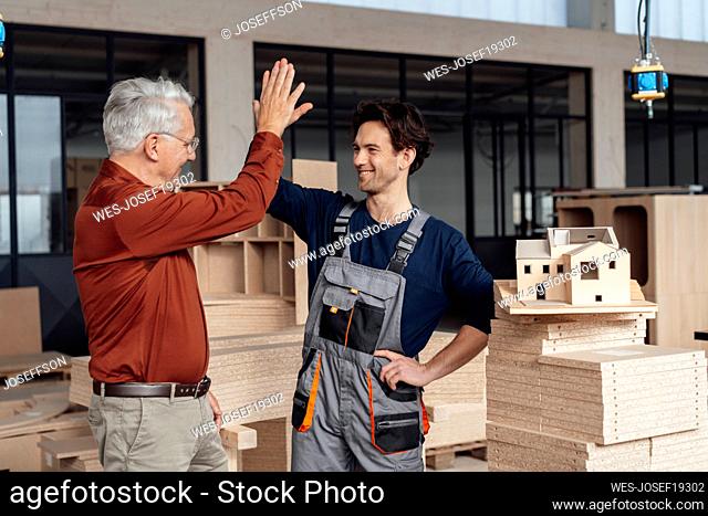 Happy businessman giving high-five to each other in industry