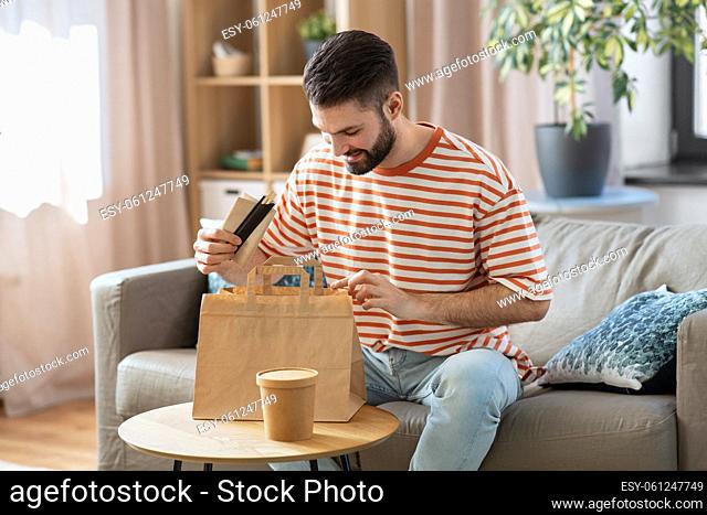 smiling man unpacking takeaway food at home