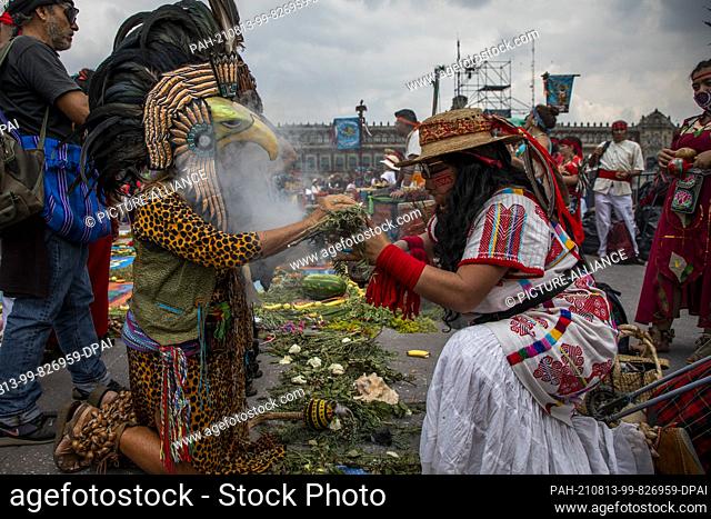 12 August 2021, Mexico, Mexiko-Stadt: A woman performs a purification ritual on a person depicted as an Aztec warrior during the commemoration of the fall of...