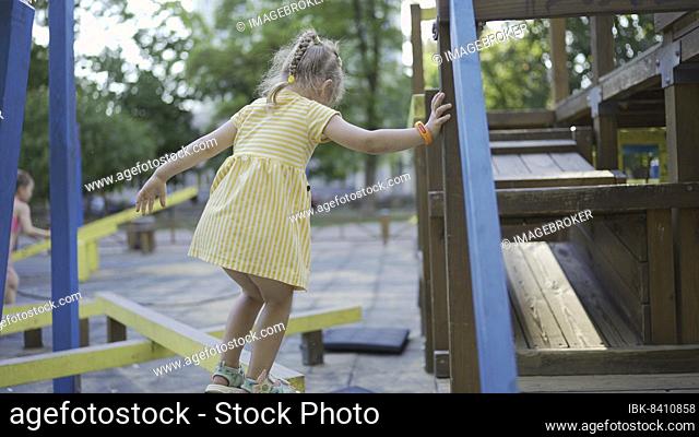 Cute little girl plays on the playground. Child girl playing on the playground in the city park. Odessa, Ukraine, Europe
