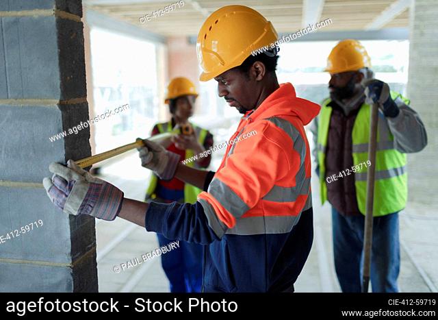 Construction workers with tape measure at construction site