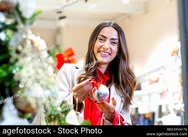 Happy young woman holding decoration in shop