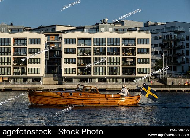 Stockholm, Sweden A classic wooden boat with a Swedish flag passes Grondal