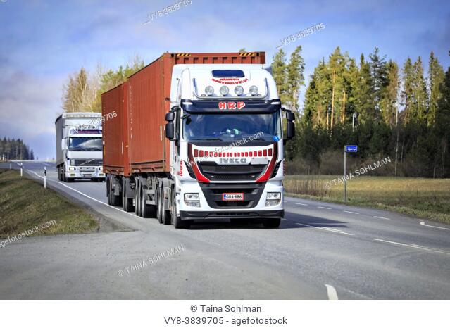 Iveco Stralis and Volvo heavy trucks pulling freight trailers along highway on a day of spring. Jokioinen, Finland. April 29, 2021