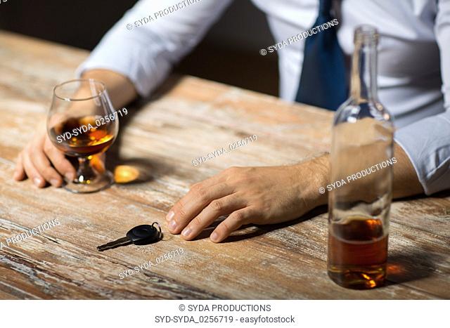 close up of man with alcohol and car key at night