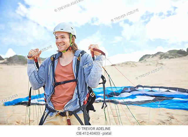 Smiling, confident paraglider with parachute on beach