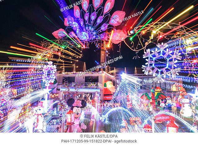 Dozens of illuminated Christmas figures and motives, as well as thousands of lights fill the front garden of a house while music completes the experience for...