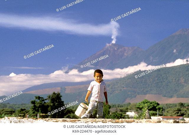 Mayan boy and the Volcán de Fuego in background. Antigua Guatemala. Guatemala