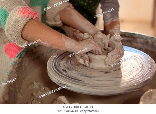 Girls making pot in pottery workshop