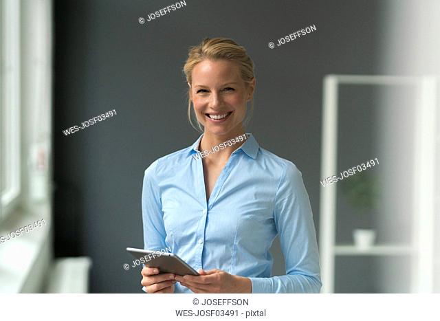 Portrait of smiling young businesswoman with tablet in office