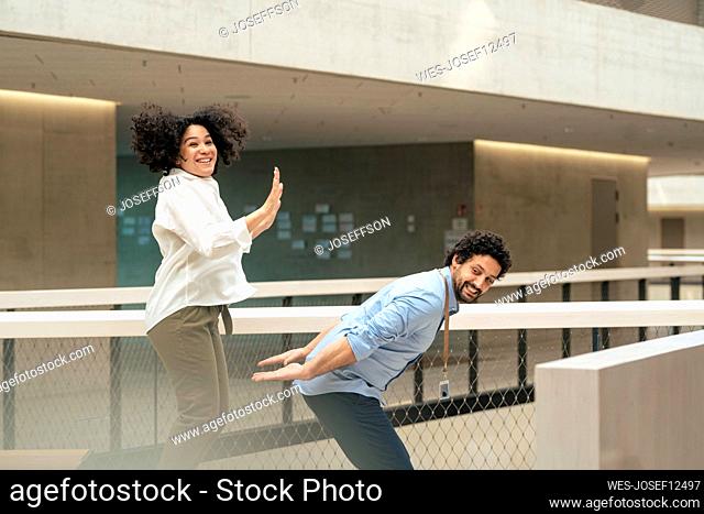 Happy businesswoman giving high-five to colleague in corridor