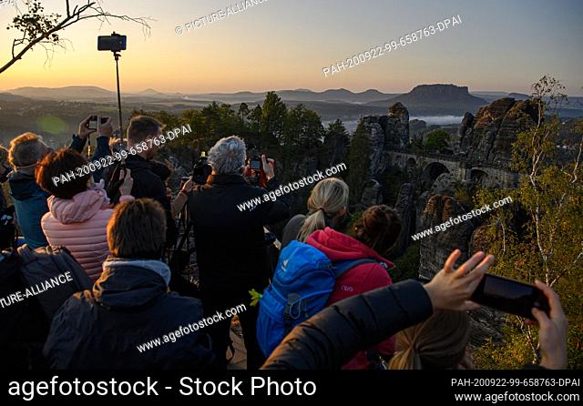 22 September 2020, Saxony, Rathen: In the early morning, numerous tourists stand on a viewing platform in the Saxon Switzerland National Park in front of the...