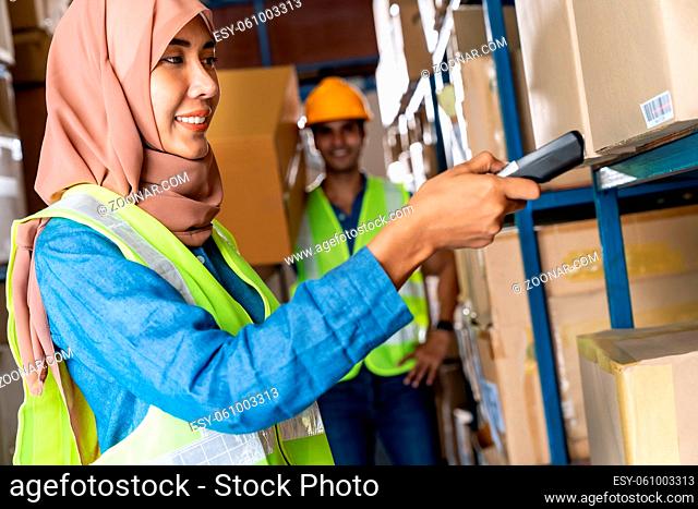 Asian Islam Muslim female warehouse worker do inventory with barcode scanner with Indian worker hold cardboard box in warehouse distribution