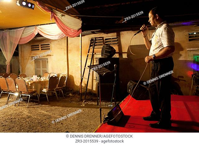 A wedding guest sings karaoke to empty seats at buddhist wedding in a small village outside of Phnom Penh, Cambodia