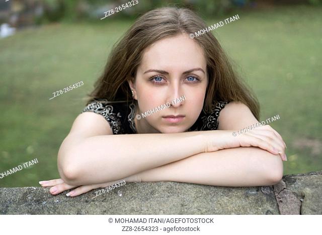 Serious young woman leaning on her arms outdoors