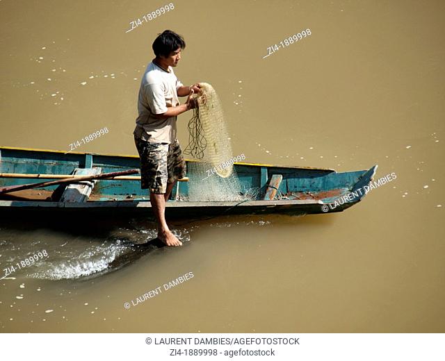 Fisherman on his boat holding a net on the Mekong River in Luang Prabang
