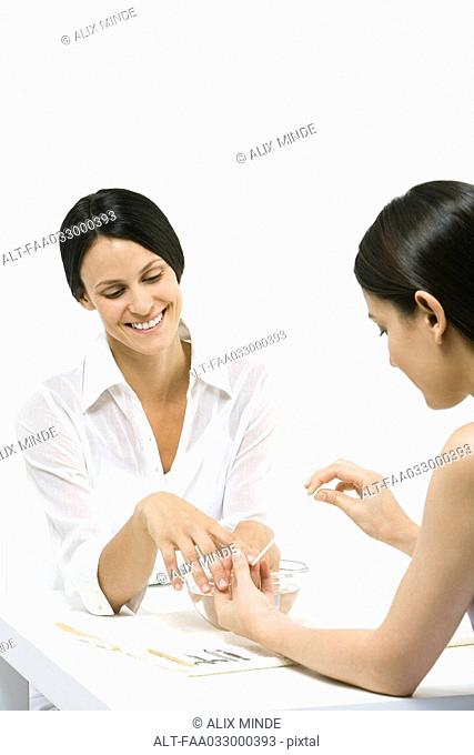 Woman receiving manicure, smiling