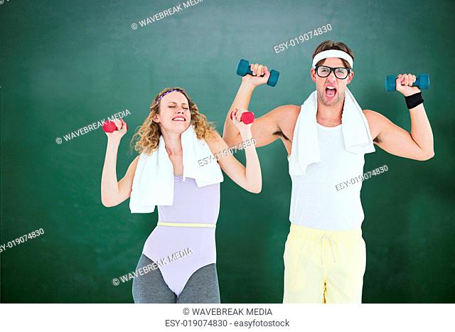 Composite image of geeky hipster couple lifting dumbbells in sportswear