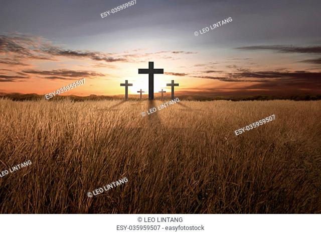 Bright christian cross at sunset on meadow field