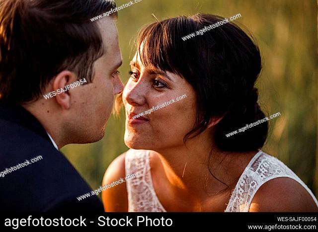 Close-up of bridal couple looking at each other during sunset