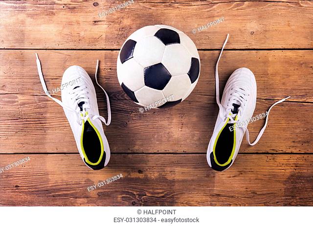 Football boots and ball laid on a wooden floor background