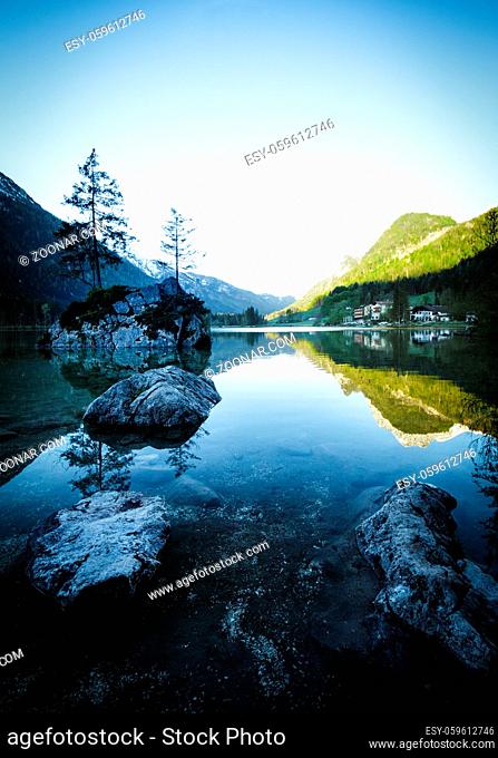 Fantastic sunrise at Hintersee lake. Beautiful scene of trees on a rock island during Spring in Berchtesgaden Germany