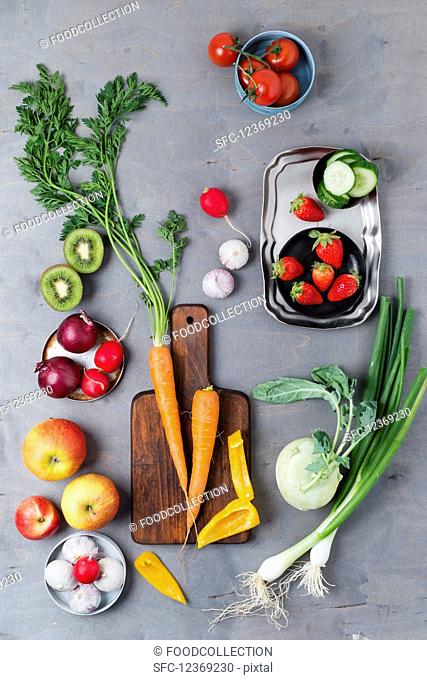 An arrangement of spring onions, garlic, apples, tomatoes, peppers, carrots, kiwi, radishes, strawberries and kohlrabi