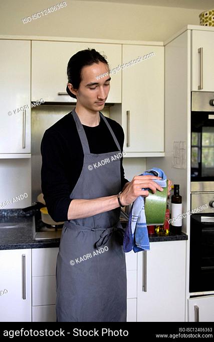 UK, Surrey, Walton-on-Thames, Man in apron in kitchen