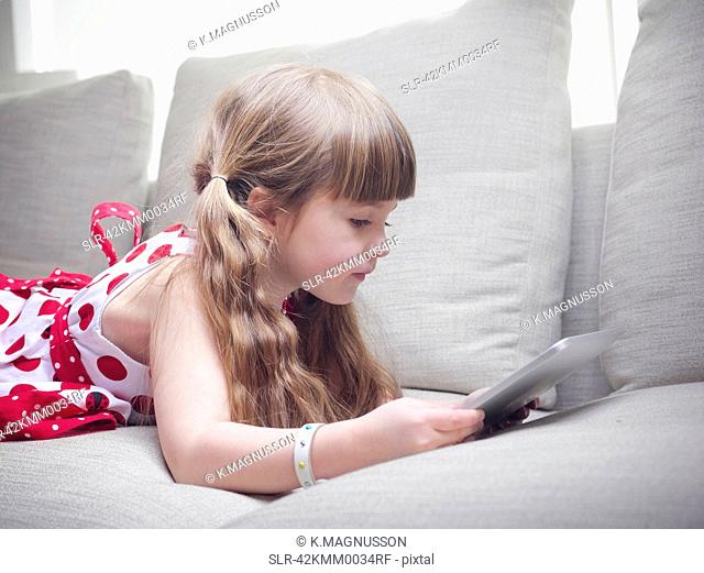 Girl using tablet computer on sofa