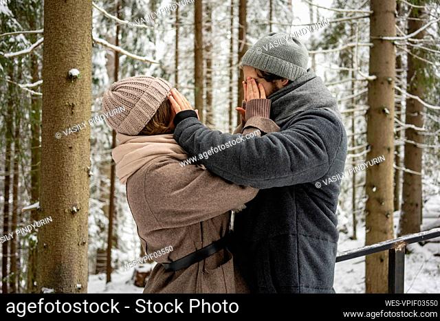Young couple covering each other eyes while standing in forest