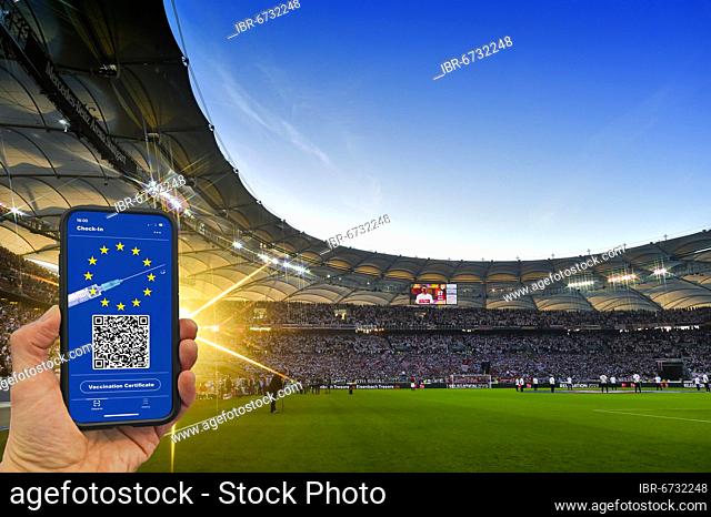 PHOTOMONTAGE, hand holding smartphone with digital European vaccination card in packed football stadium, symbolic image, Corona crisis, Mercedes-Benz Arena