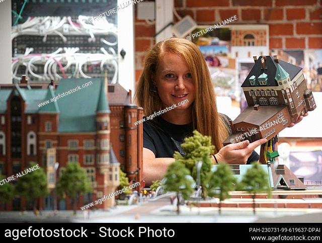 PRODUCTION - 18 July 2023, Hamburg: Model maker Tanja Schlabitz holds up the new Speicherstadt moated castle in the Miniatur Wunderland workshop