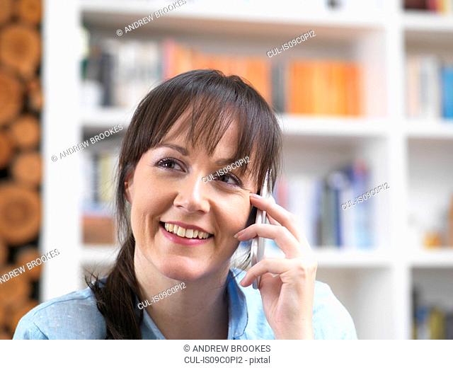 Woman relaxing and catching up with friends over the phone in her lounge