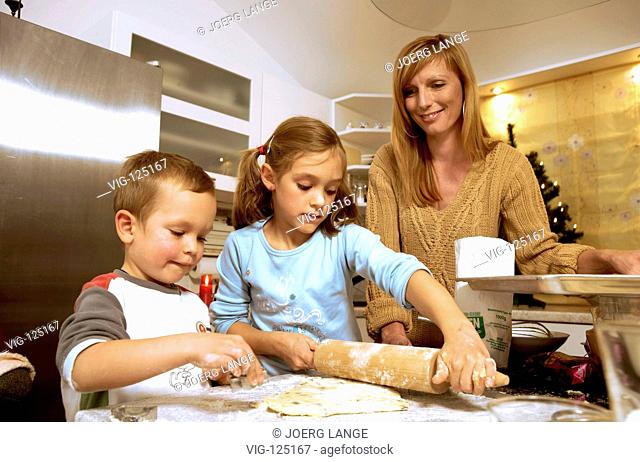A young mother is baking christmas cookies with her children. - LEIPZIG, GERMANY, 18/10/2005