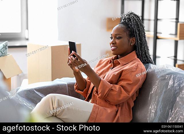 woman with smartphone and boxes moving to new home