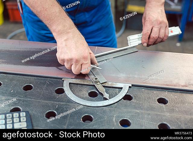 Metalworker using folding rule to measure steel strip for later cutting