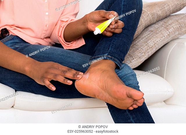 Close-up Of Person's Hand Applying Cream On Feet