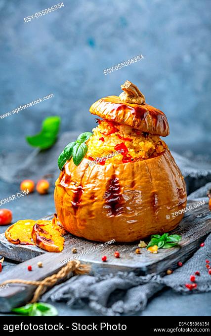 Pumpkin baked with couscous, carrots, sweet peppers and leeks on a wooden serving board, selective focus
