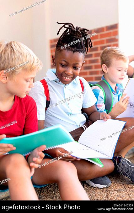 Smiling african american elementary schoolboy studying with caucasian classmate in school