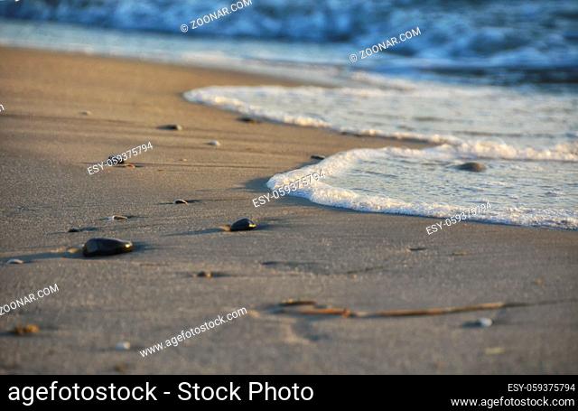 Sandstrand mit von Wellen überspülten Steinen