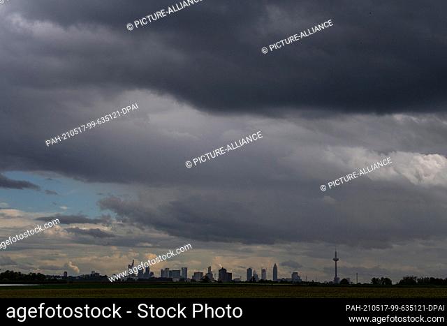 17 May 2021, Hessen, Nieder-Erlenbach: Dark storm and thunder clouds pass over the skyline of Frankfurt am Main. Photo: Boris Roessler/dpa