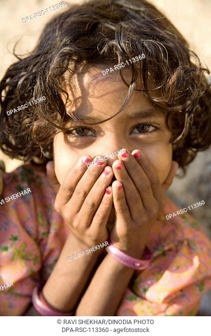 Rural girl put hands on mouth Bheel tribal community ; semi urban village Dilwara ; Udaipur ; Rajasthan ; India