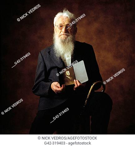 100 year old man holding portrait of self at 25 years old