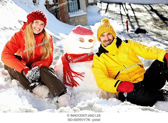 Couple sitting by snowman
