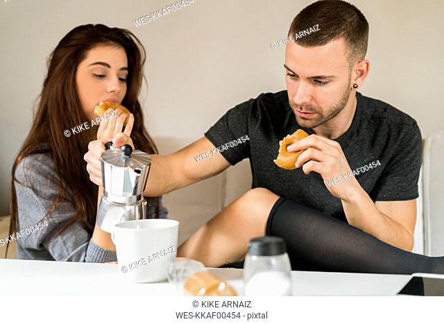 Amorous couple sitting on couch, having breakfast