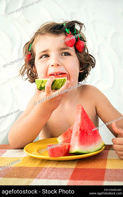 Hungry cute girl devours watermelon slices, refreshing summer dessert. Has strawberry hair clips acting being goofy funny